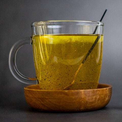  A hand holding a tea ball over a steaming cup of tea